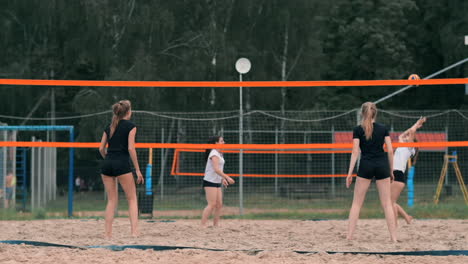 Junge-Frau-Spielt-In-Einer-Mannschaft-Volleyball-Am-Strand-Und-Führt-Einen-Angriff-Durch,-Indem-Sie-Den-Ball-Schlägt.-Mädchen-Schlägt-In-Zeitlupe-Den-Ball-Und-Führt-Einen-Angriff-Durch-Das-Netz-Aus.